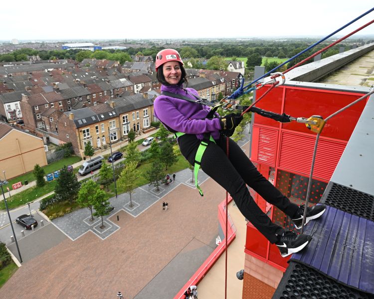 woman about to abseil down the side of anfield stadium