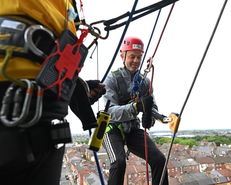 man about to abseil down the side of anfield stadium