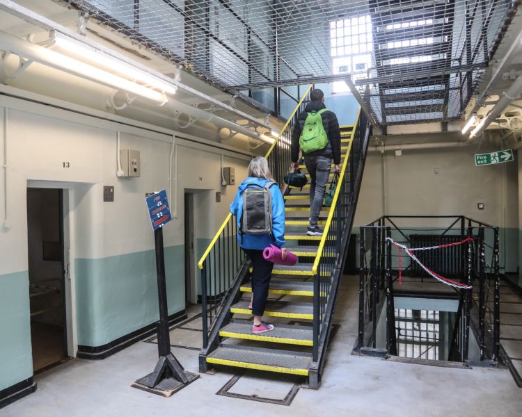 two people walking up stairs to their prison cell as part of a night behind bars experience