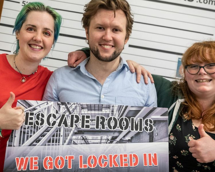 three people smiling having completed a prison escape room experience day
