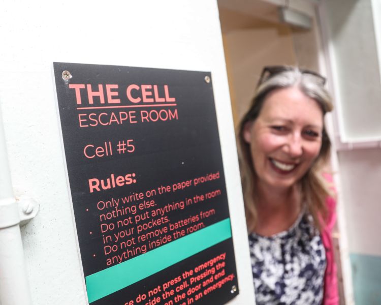 woman looking around a cell door on a prison escape room experience day