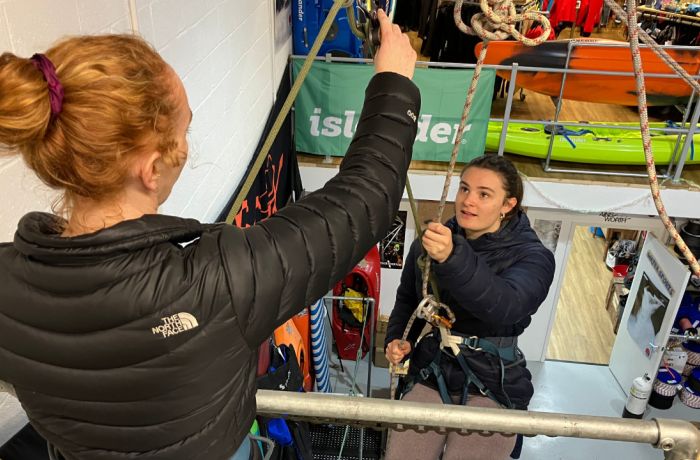 woman about to abseil down an indoor wall with instructor looking on on an abseiling taster session in brighton