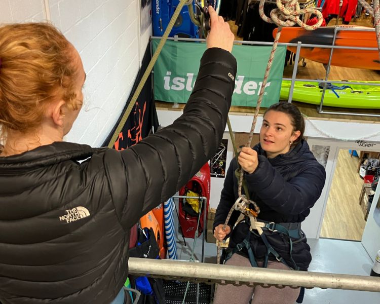 woman about to abseil down an indoor wall with instructor looking on on an abseiling taster session in brighton