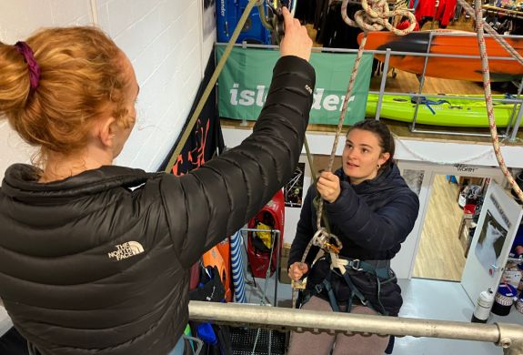 woman about to abseil down an indoor wall with instructor looking on on an abseiling taster session in brighton