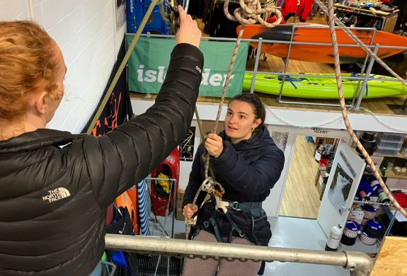 woman about to abseil down an indoor wall with instructor looking on on an abseiling taster session in brighton