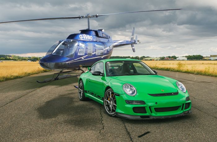 a green sports car on a track with a helicopter behind it for a fly and drive experience day