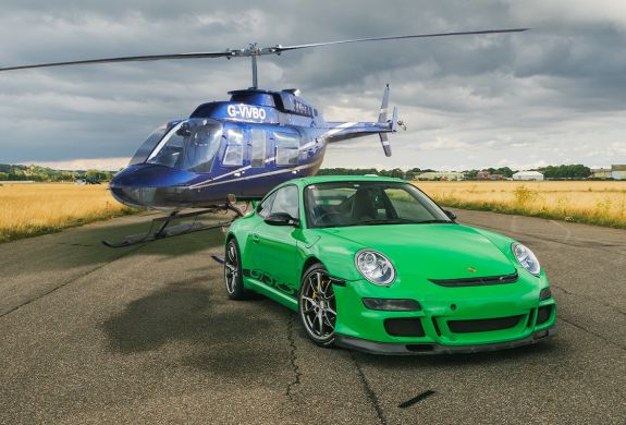 a green sports car on a track with a helicopter behind it for a fly and drive experience day