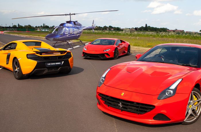 three supercars on a track with a helicopter in the background