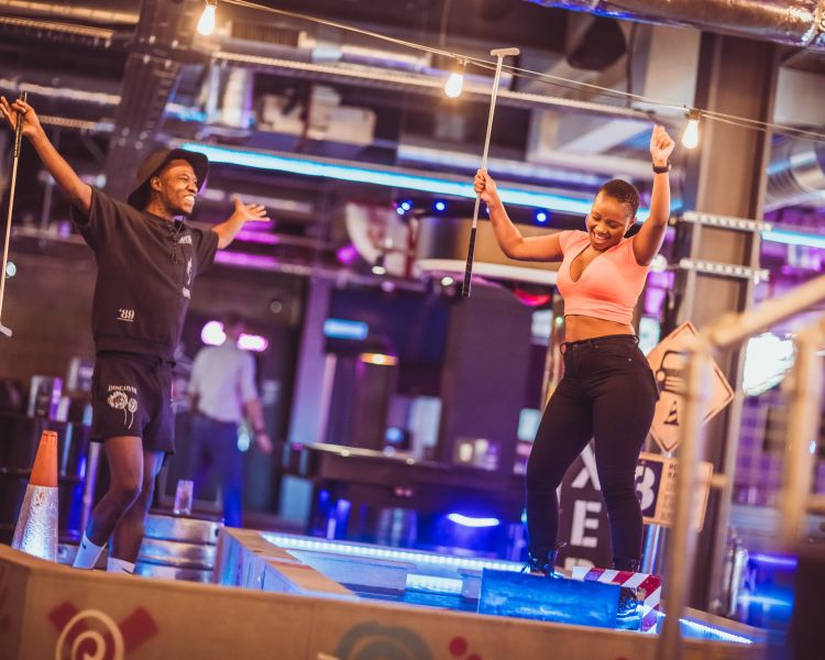 man and woman having fun playing crazy golf at a boom battle bar