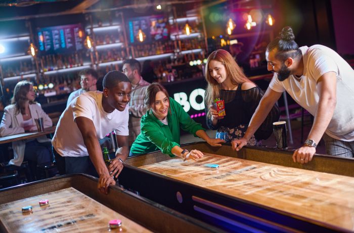 friends playing shuffleboard at a boom battle bar