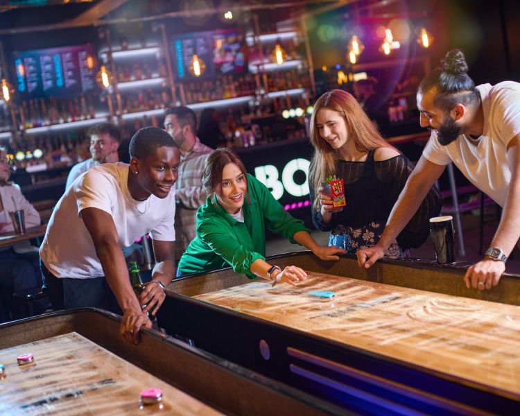friends playing shuffleboard at a boom battle bar