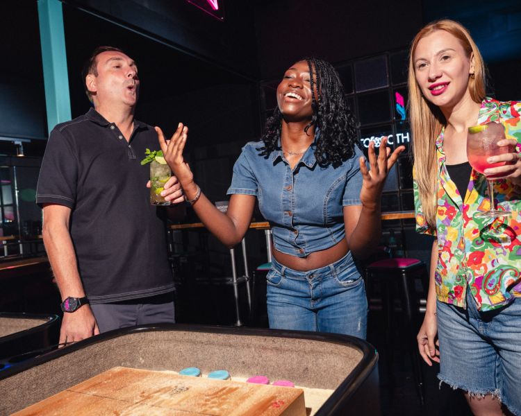 friends playing shuffleboard at a boom battle bar