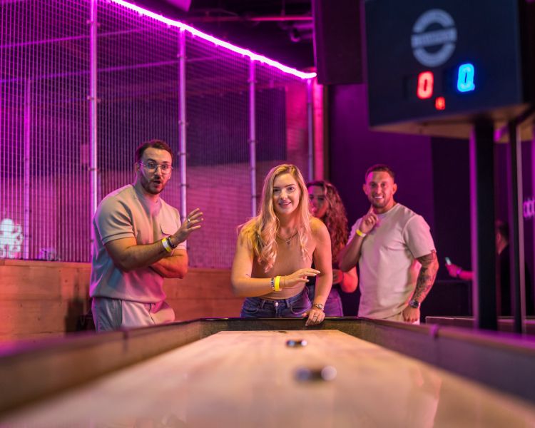 friends playing shuffleboard at a boom battle bar