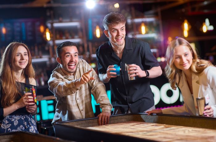 friends playing shuffleboard at a boom battle bar