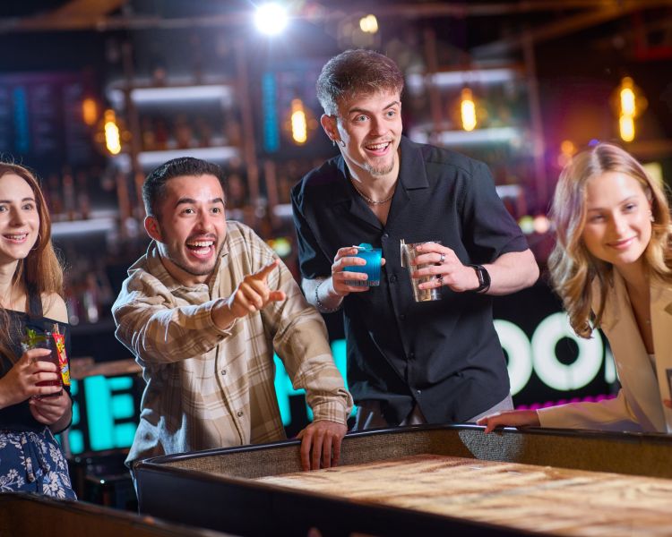 friends playing shuffleboard at a boom battle bar