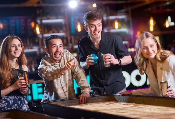 friends playing shuffleboard at a boom battle bar