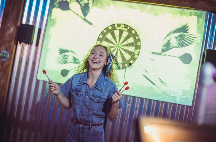 woman playing darts at a boom battle bar