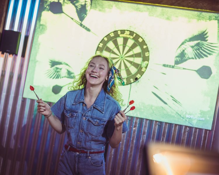 woman playing darts at a boom battle bar