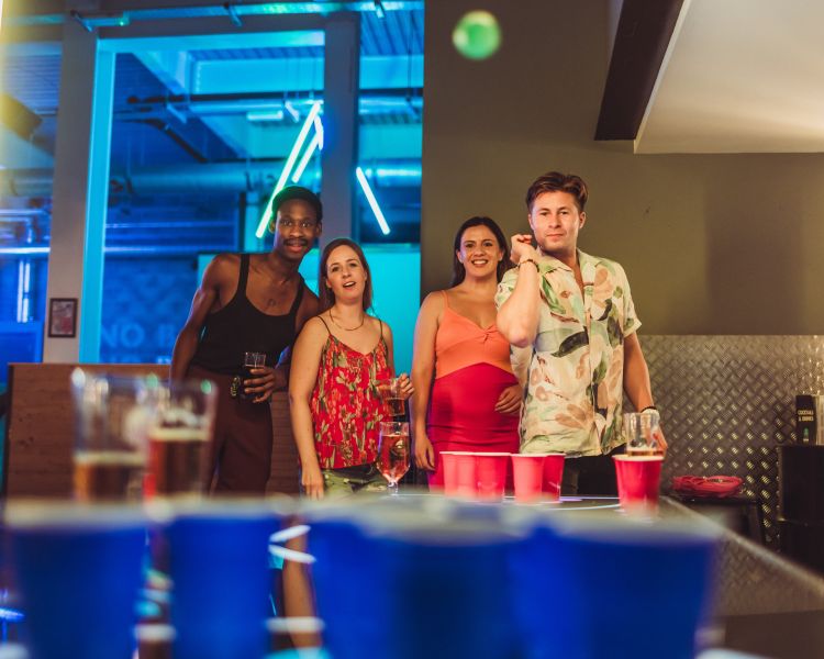 friends playing beer pong at a boom battle bar