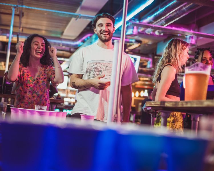 friends playing beer pong at a boom battle bar