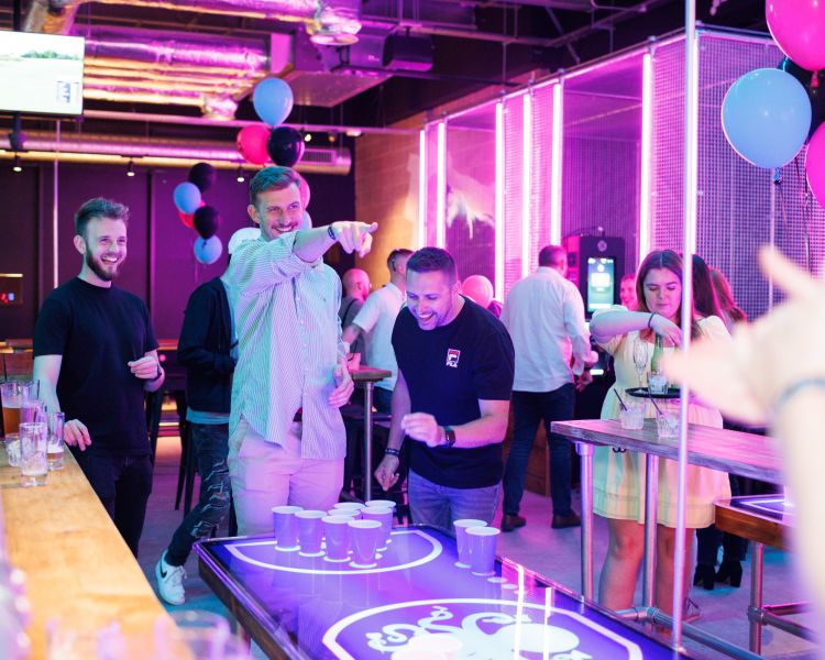 friends playing beer pong at a boom battle bar