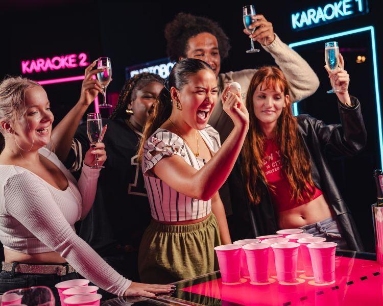 ladies playing prosecco pong at a boom battle bar