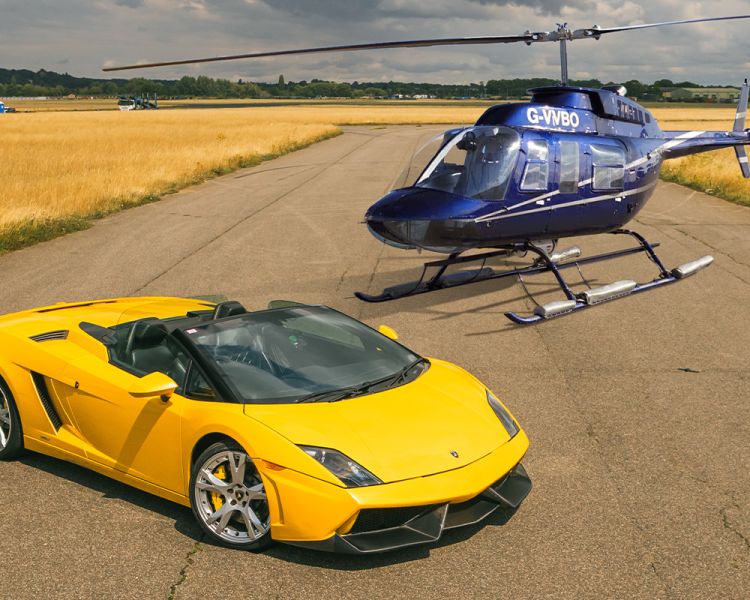 a yellow supercar on a track with a blue helicopter behind it