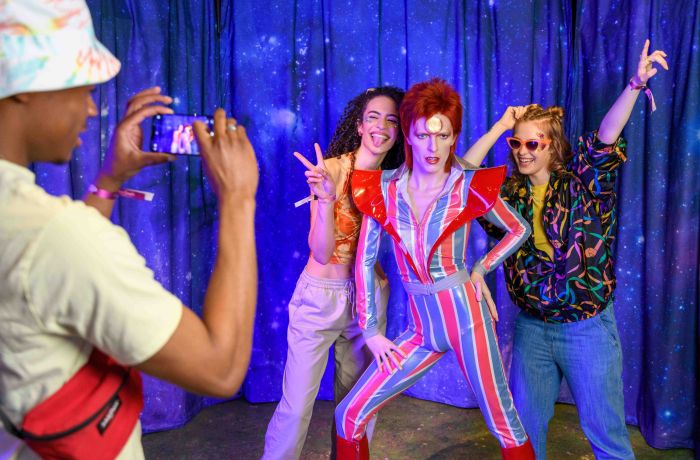 Guests pose for a picture with David Bowie figure at Madame Tussauds London