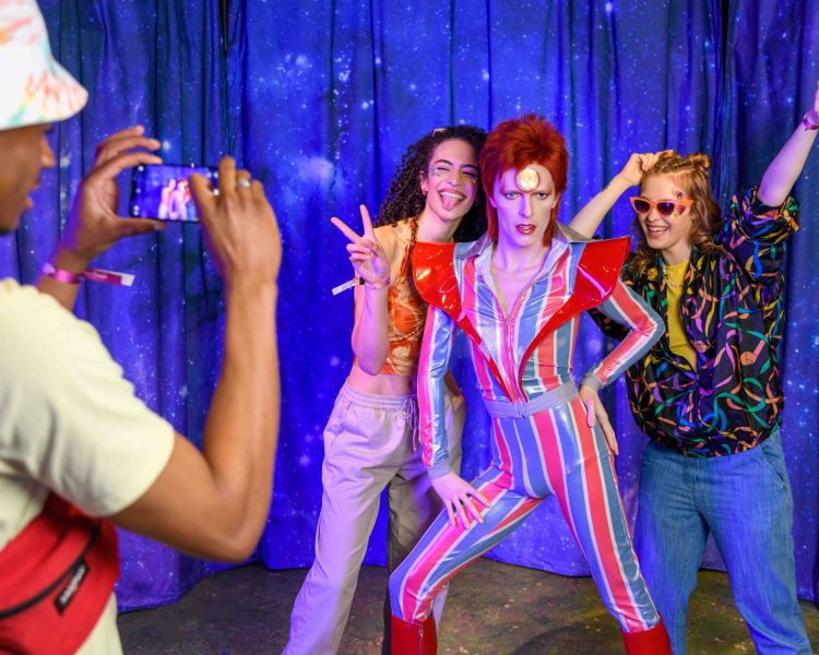Guests pose for a picture with David Bowie figure at Madame Tussauds London