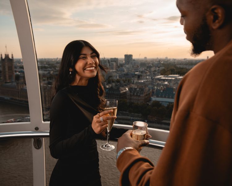 couple on the london eye at sunset drinking champagne