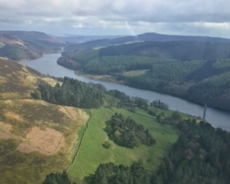 view from out of a helicopter overlooking a winding river through woodland