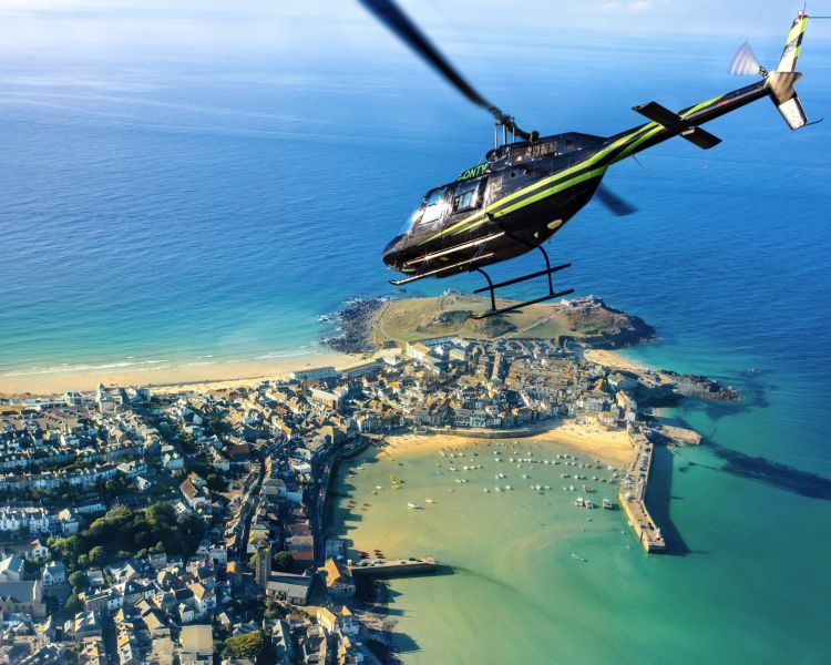 helicopter flying over the cornish coastline