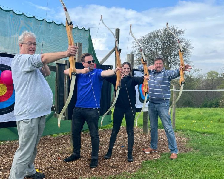 Group of people holding bows on archery experience