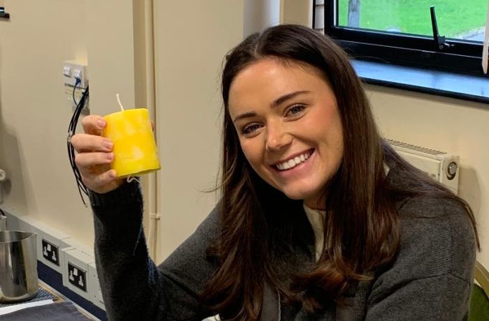 Woman smiling holding the candle she has made at candle making workshop
