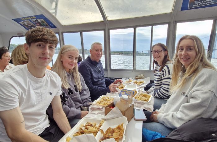 family enjoying fish and chips on a river cruise