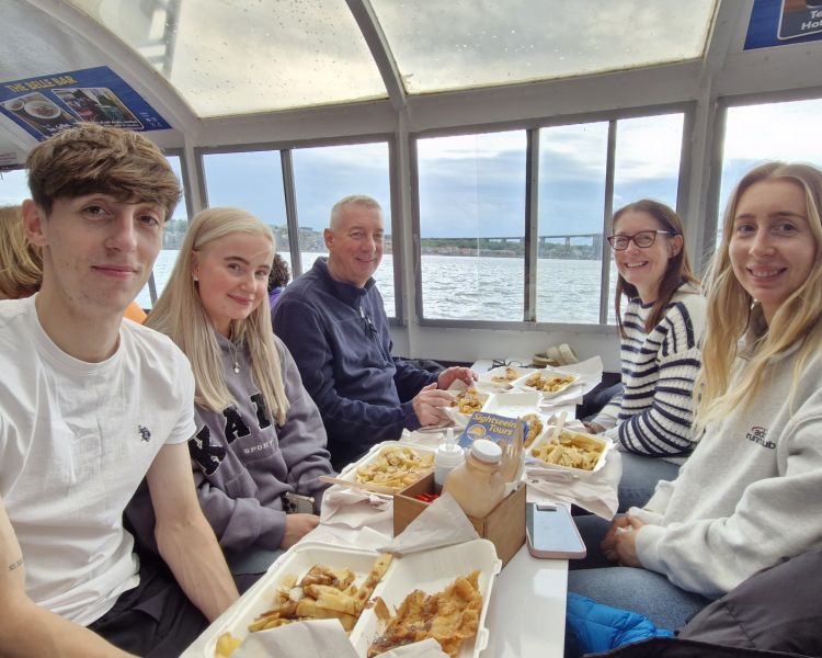 family enjoying fish and chips on a river cruise