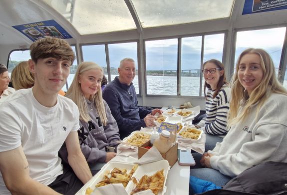 family enjoying fish and chips on a river cruise
