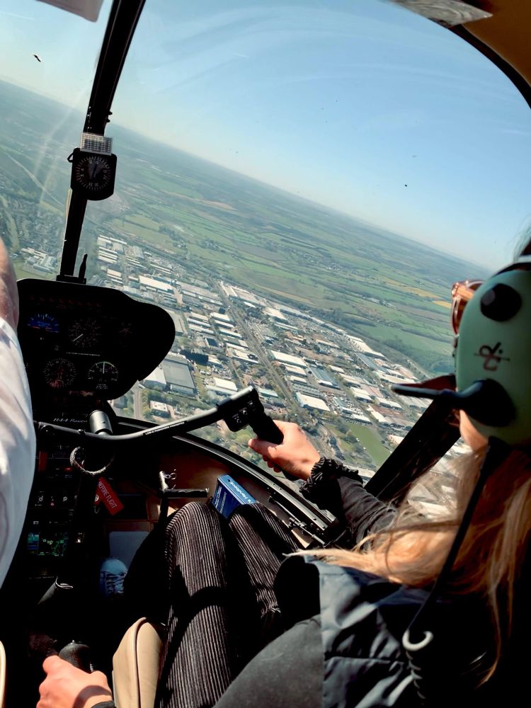 person at controls of a helicopter looking out over town and countryside