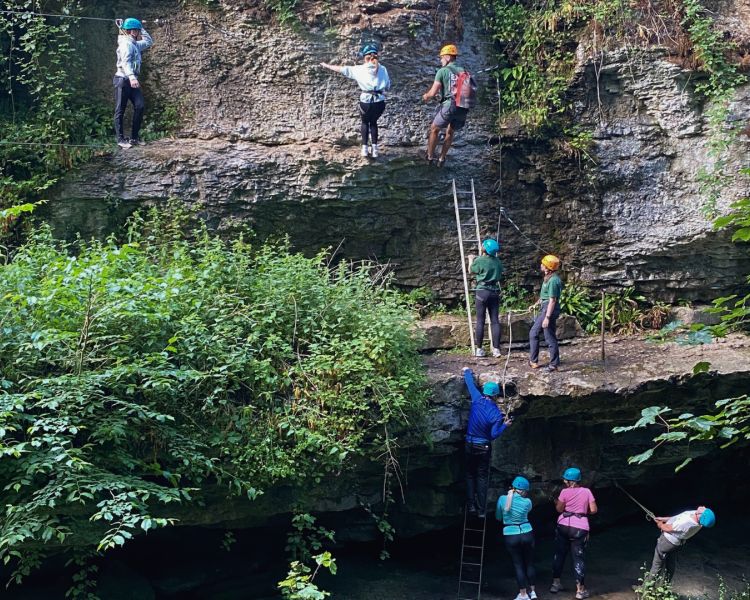 people abseiling down a cliff face in a gorge overlooking a river