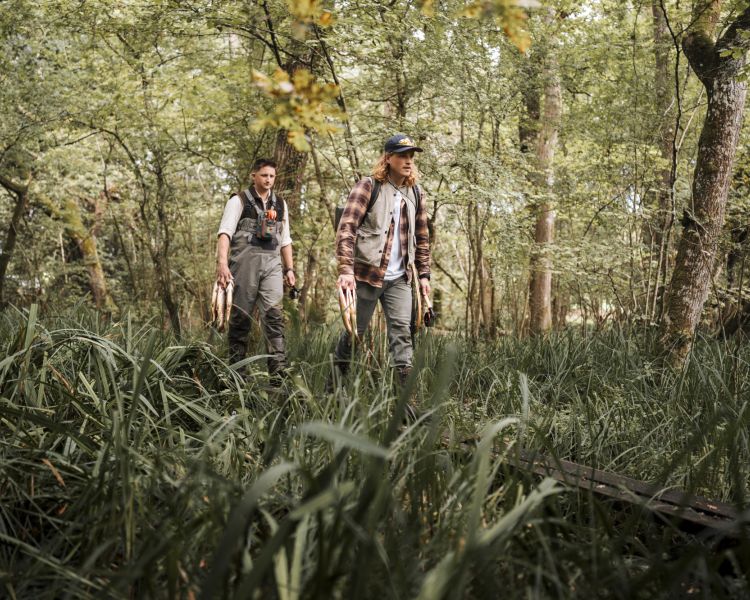 two men walking alongside a river on a fishing trip