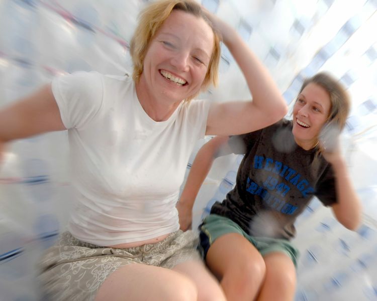 two women laughing inside an aqua sphere on an aqua sphereing experience day