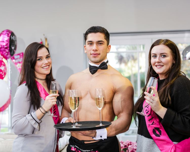 Butler posing with two ladies with glasses of prosecco