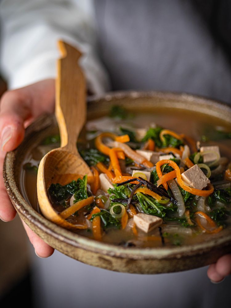 person holding a bowl of noodle soup