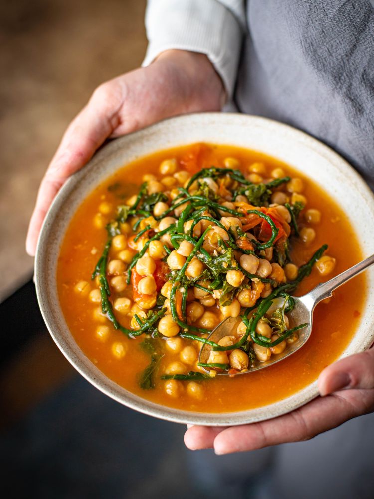 person holding a bowl of chickpea curry