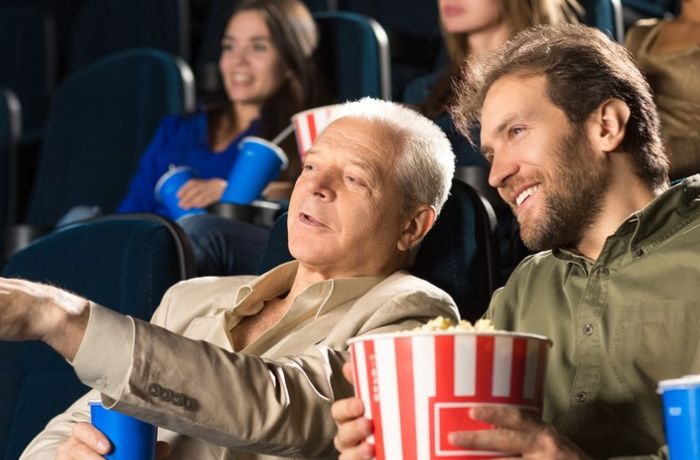 father and son watching film at odeon cinema eating popcorn