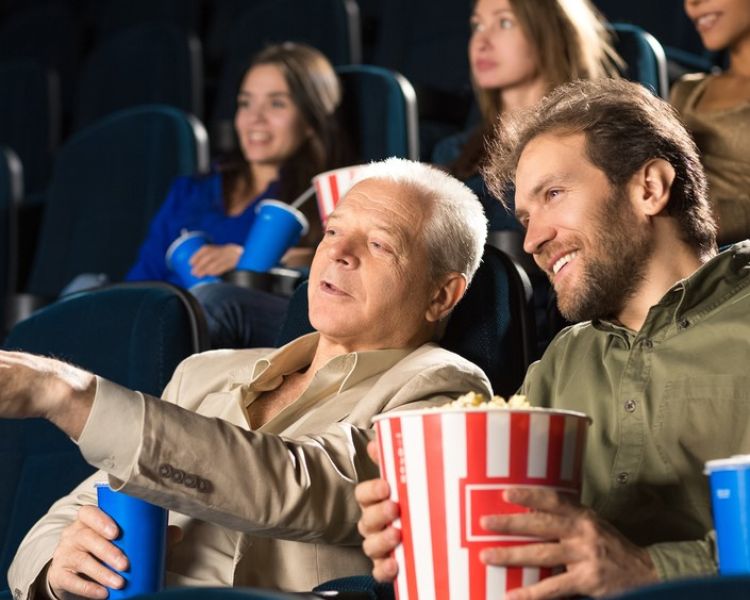 father and son watching film at odeon cinema eating popcorn