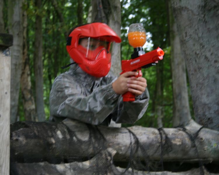 boy aiming gun on gel ball experience on woodland course