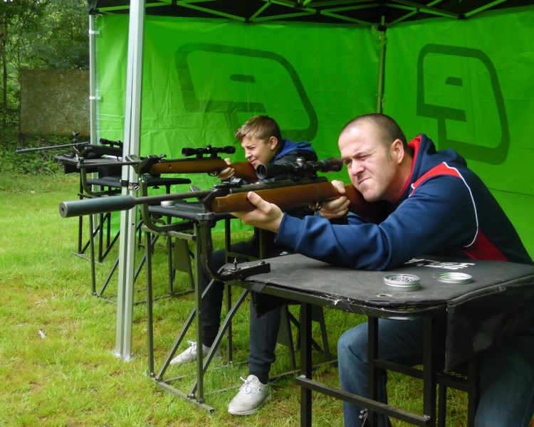 man and boy shooting air rifles on a target shooting experience