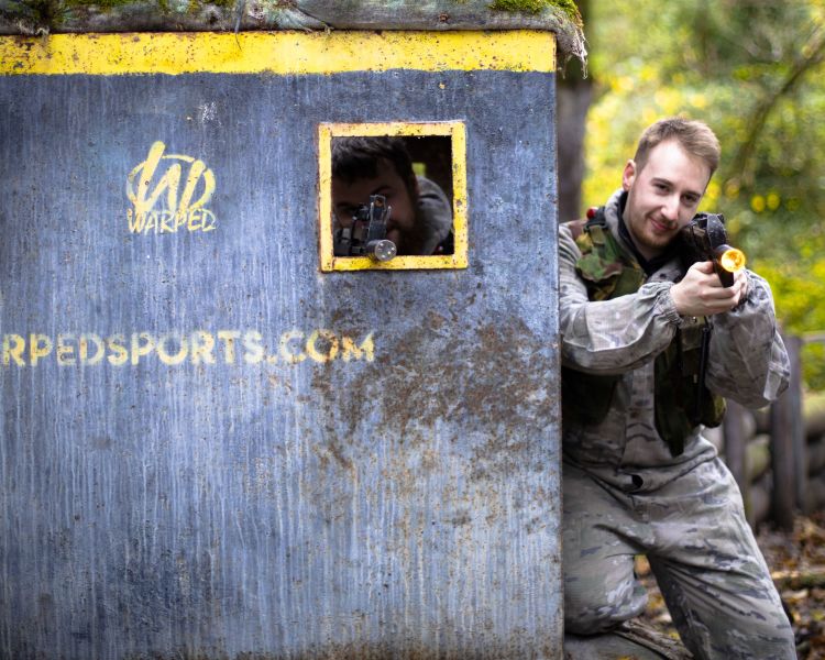 men hiding behind bunker on outdoor laser combat experience in woodland