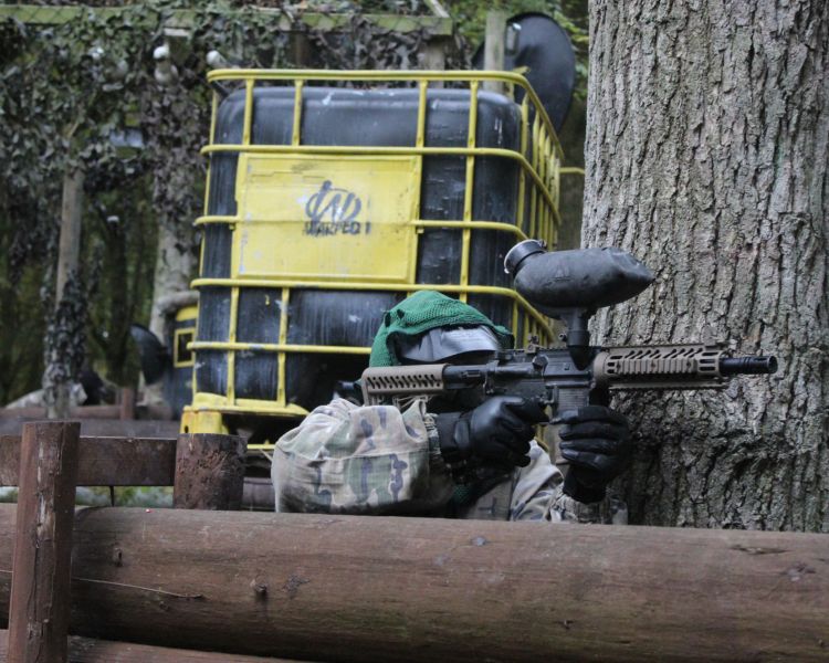 man hiding by tree on paintball experience wolverhampton